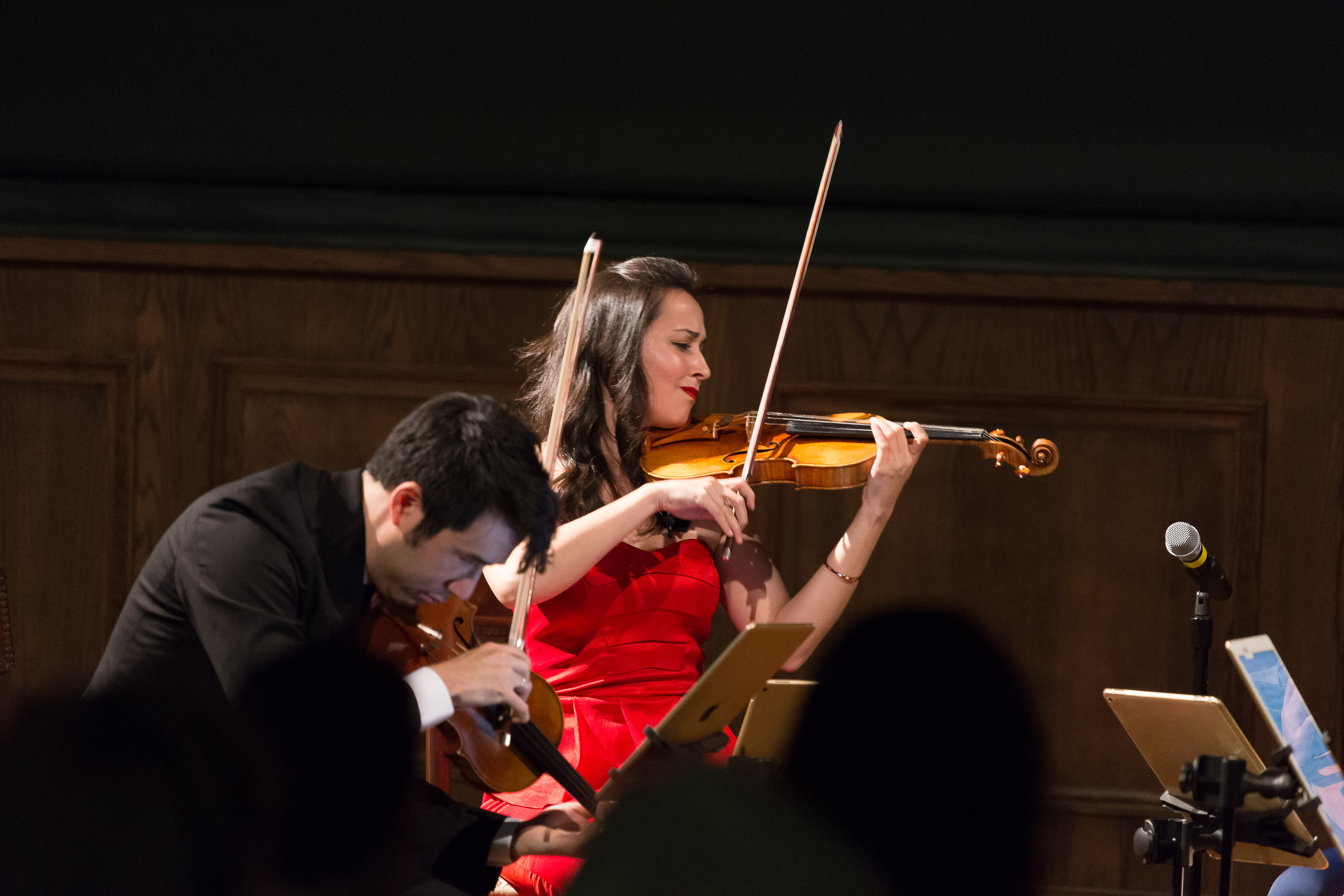 A man and a woman playing violins at a concert